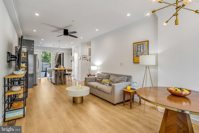 living area with crown molding, recessed lighting, ceiling fan with notable chandelier, and light wood-type flooring