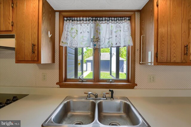 115 Penn St, Millheim, PA 16854 - kitchen with brown cabinets, a sink, light countertops, wallpapered walls, and range hood