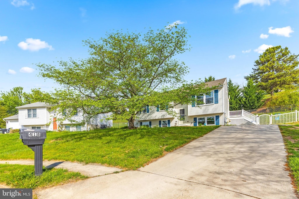 raised ranch with fence, a front yard, and concrete driveway