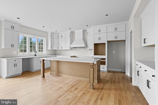 kitchen featuring custom exhaust hood, light wood-style flooring, and white cabinetry