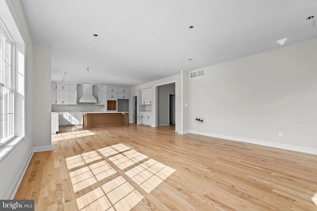 unfurnished living room with baseboards, visible vents, and light wood-style flooring