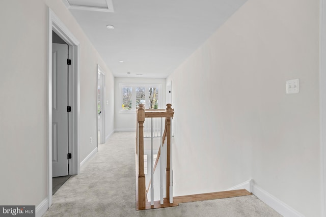 hallway featuring an upstairs landing, attic access, baseboards, and light carpet