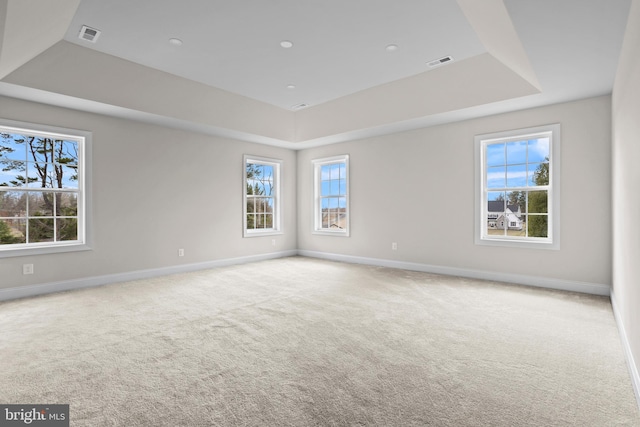 spare room featuring visible vents, carpet floors, a raised ceiling, and baseboards