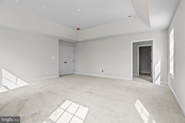 unfurnished room featuring baseboards, visible vents, light colored carpet, and a tray ceiling