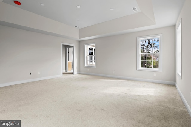unfurnished room featuring a raised ceiling, visible vents, baseboards, and light carpet
