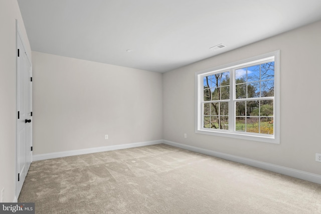 empty room with visible vents, light carpet, and baseboards
