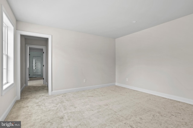 carpeted empty room featuring baseboards