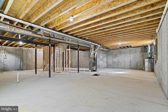 unfinished below grade area featuring heating unit and water heater