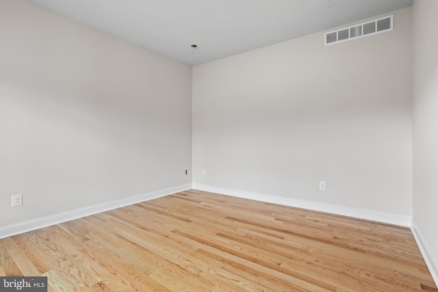 unfurnished room featuring visible vents, wood finished floors, and baseboards