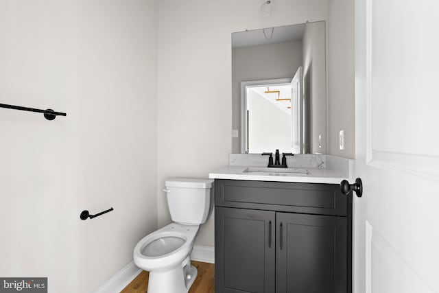 bathroom featuring wood finished floors, toilet, and vanity