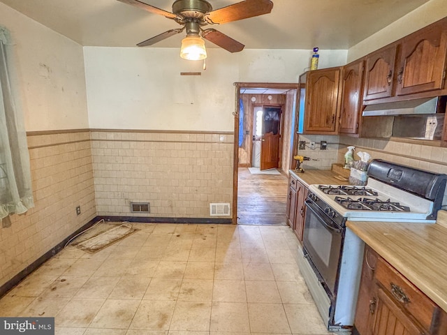kitchen with visible vents, light countertops, under cabinet range hood, and range with gas stovetop