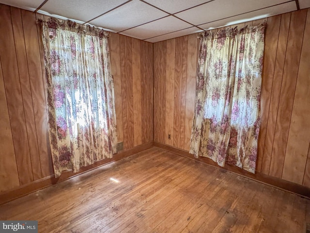 spare room featuring hardwood / wood-style floors, baseboards, and wood walls