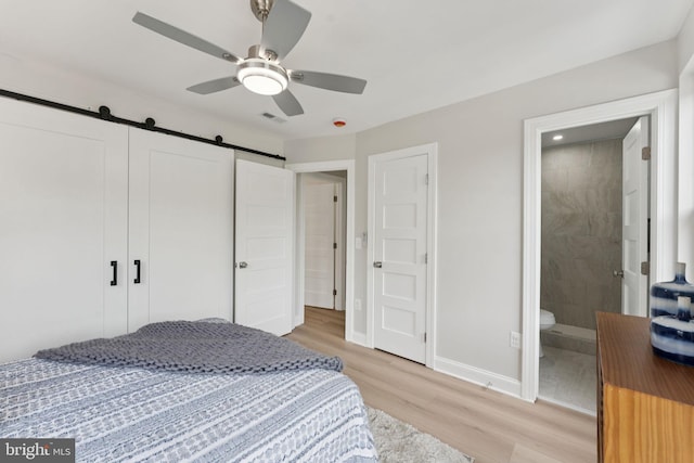 17 Longfellow St NW, Washington, DC 20011 - bedroom with light wood-type flooring, a barn door, ceiling fan, and ensuite bath