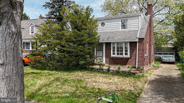 view of front of home featuring a front lawn, a chimney, and brick siding