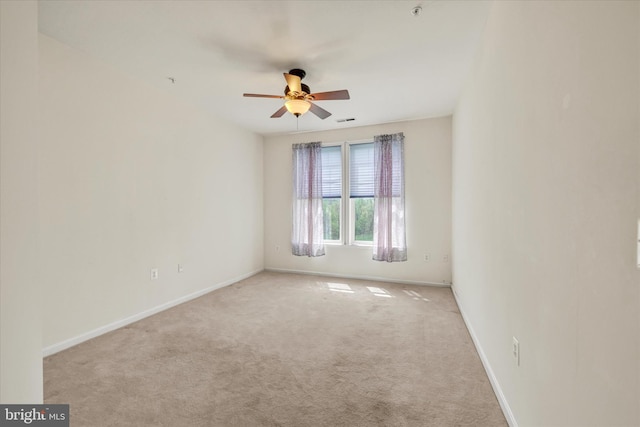 carpeted spare room with ceiling fan, visible vents, and baseboards