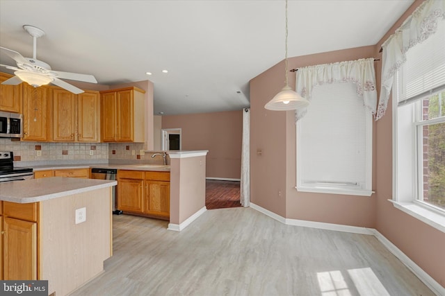 kitchen featuring decorative backsplash, appliances with stainless steel finishes, light countertops, light wood finished floors, and a sink
