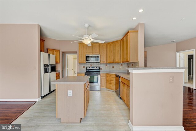 kitchen with decorative backsplash, appliances with stainless steel finishes, light countertops, recessed lighting, and a ceiling fan