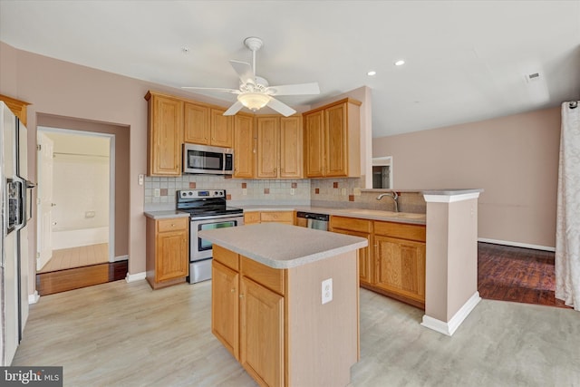 kitchen with light wood-style floors, stainless steel appliances, light countertops, and backsplash