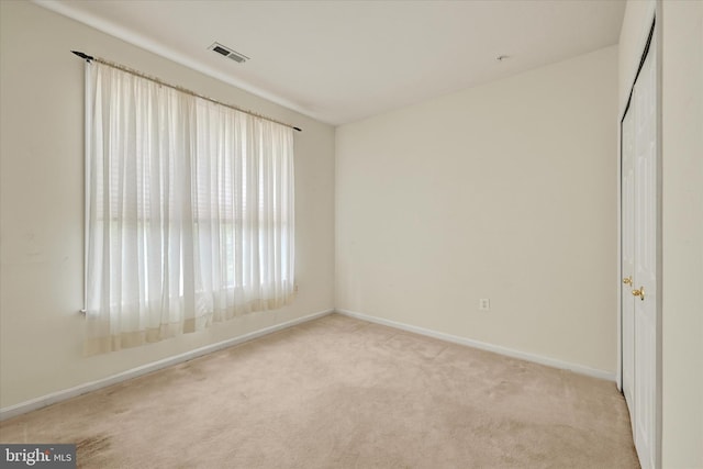 unfurnished room featuring baseboards, visible vents, and light carpet