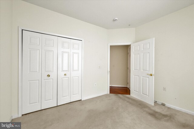 unfurnished bedroom featuring baseboards, carpet floors, and a closet