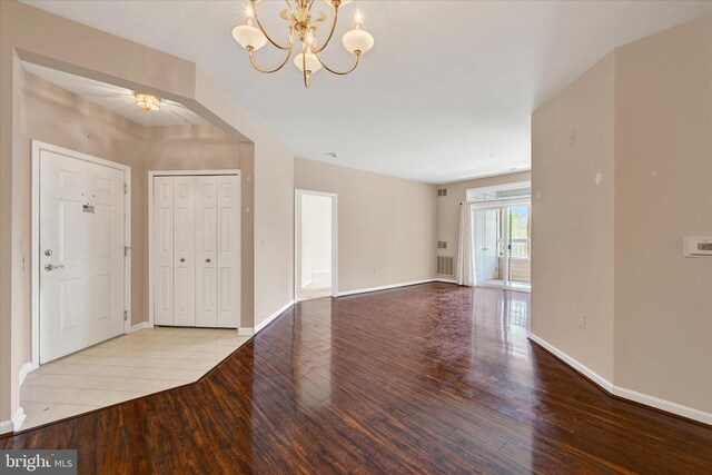 foyer entrance featuring visible vents, hardwood / wood-style floors, a notable chandelier, and baseboards