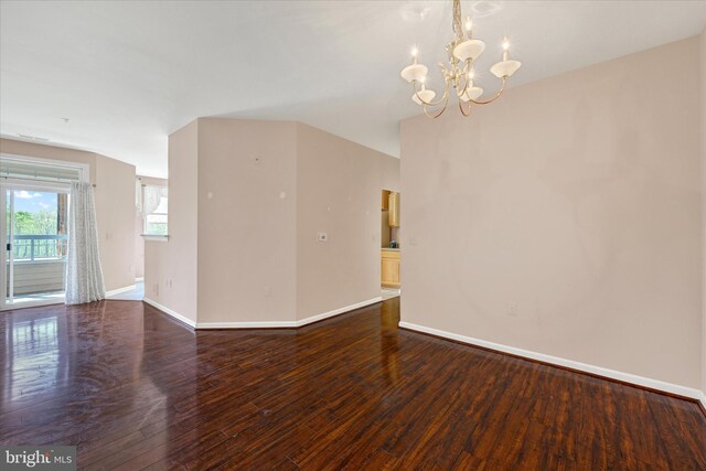 unfurnished living room with baseboards, wood finished floors, and an inviting chandelier