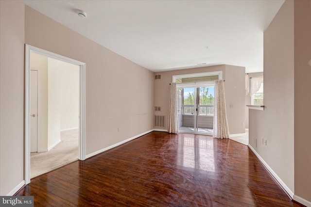 empty room featuring baseboards, visible vents, and wood finished floors