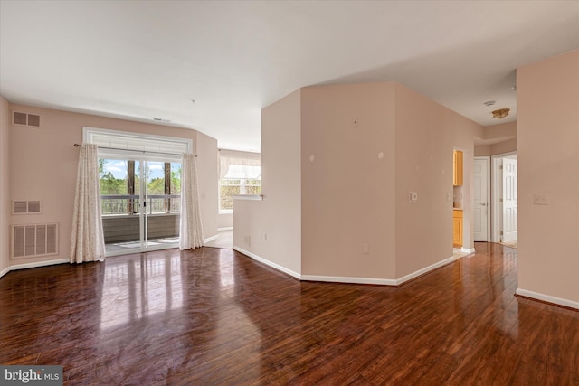 unfurnished living room with visible vents, wood finished floors, and baseboards