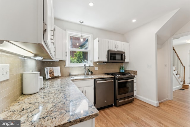 1111 Woodside Pkwy, Silver Spring, MD 20910 - kitchen featuring decorative backsplash, appliances with stainless steel finishes, light wood-type flooring, a sink, and white cabinetry