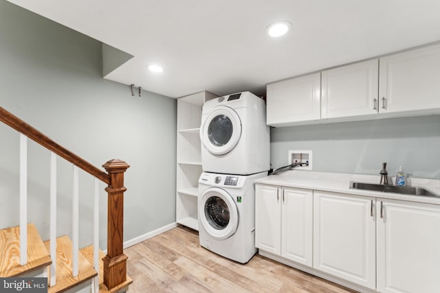 1111 Woodside Pkwy, Silver Spring, MD 20910 - washroom with stacked washer and dryer, baseboards, a sink, cabinet space, and light wood finished floors