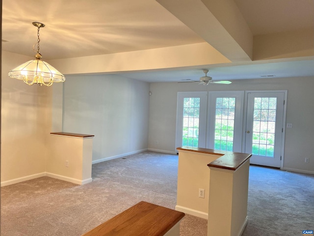 kitchen featuring ceiling fan with notable chandelier, decorative light fixtures, carpet floors, and baseboards