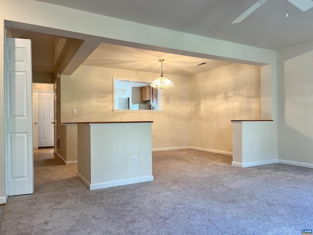 carpeted spare room with baseboards and ceiling fan with notable chandelier