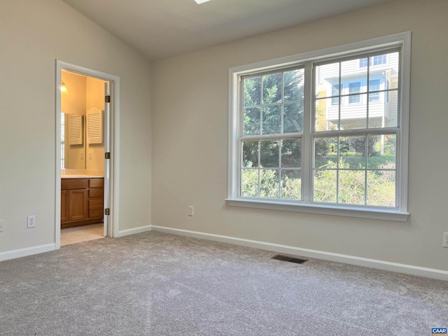empty room with light colored carpet, visible vents, and baseboards