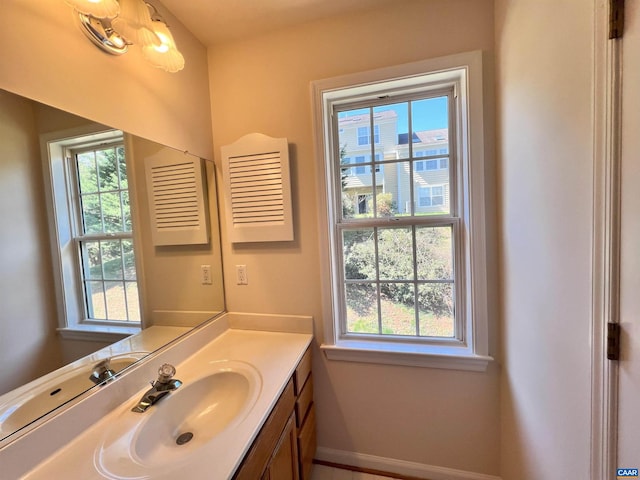 bathroom featuring baseboards, vanity, and a healthy amount of sunlight