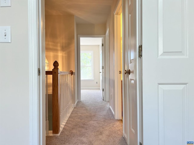 hall featuring an upstairs landing, carpet floors, and baseboards