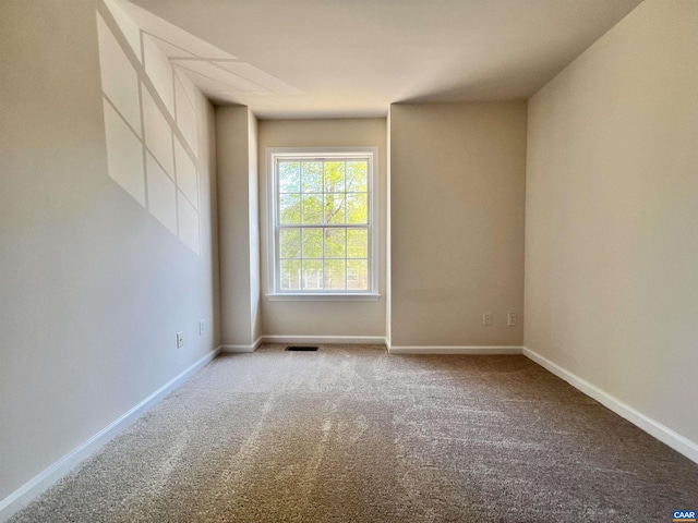 carpeted spare room with visible vents and baseboards