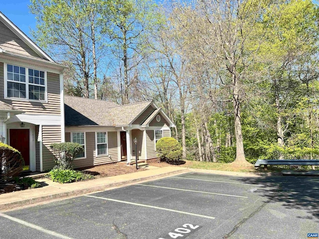 view of front facade featuring a shingled roof and uncovered parking