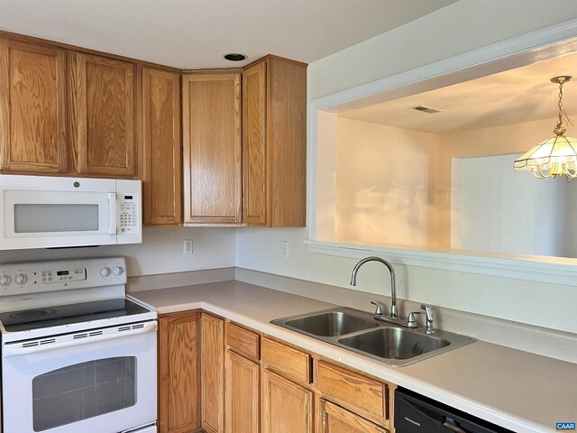 kitchen with white appliances, light countertops, a notable chandelier, and a sink