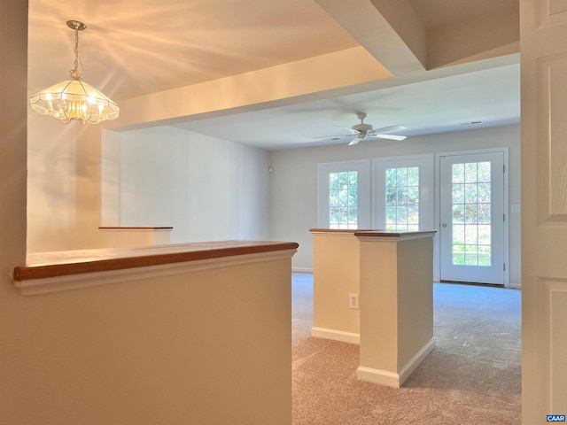 interior space featuring ceiling fan with notable chandelier, baseboards, and light carpet