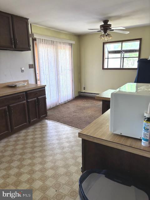 office space with plenty of natural light, a baseboard radiator, light floors, and ceiling fan