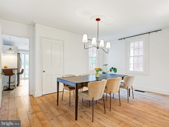 dining room with plenty of natural light, visible vents, light wood finished floors, and a notable chandelier