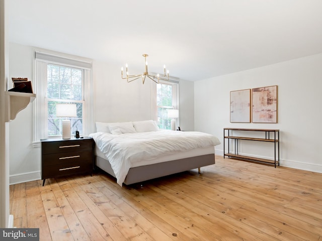 bedroom with an inviting chandelier, baseboards, and light wood-style flooring