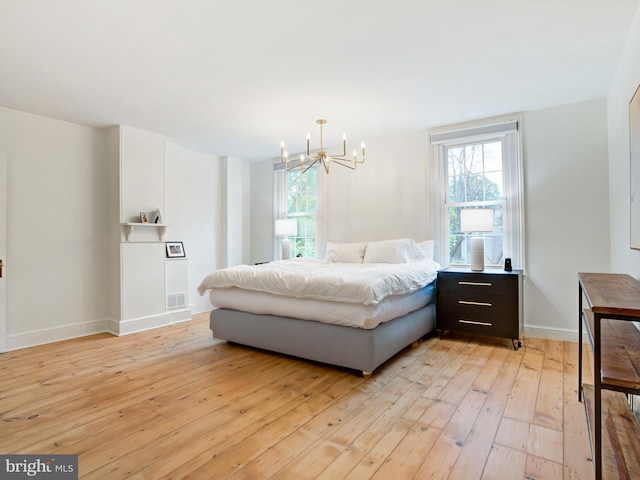 bedroom with baseboards, light wood finished floors, a notable chandelier, and multiple windows
