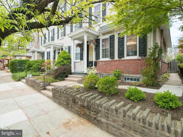 view of front of property with brick siding and fence