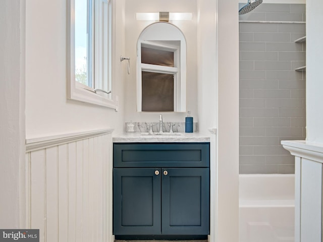 full bath with bathing tub / shower combination, a wainscoted wall, and vanity