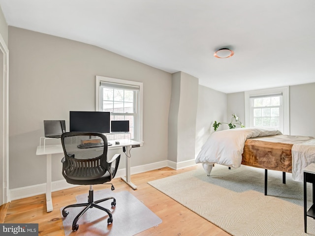 bedroom with baseboards, lofted ceiling, and wood finished floors