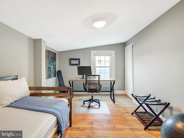 bedroom with baseboards, light wood-style flooring, and lofted ceiling