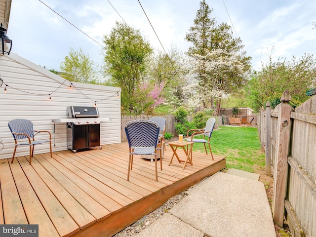 deck with a fenced backyard, a yard, and a grill