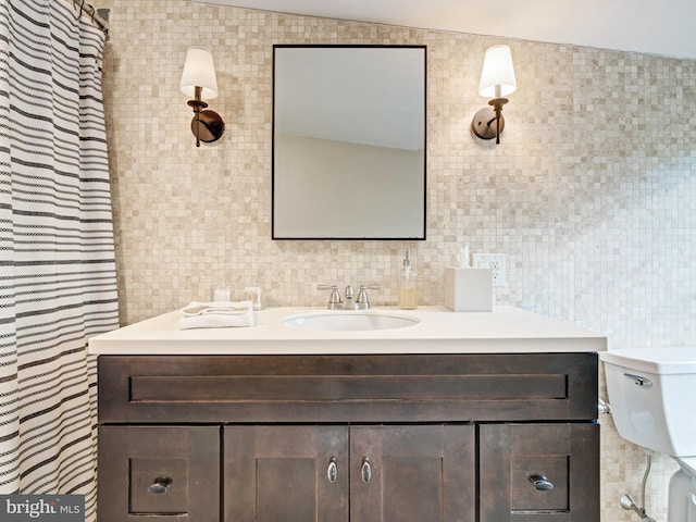 bathroom with vanity, toilet, and tile walls