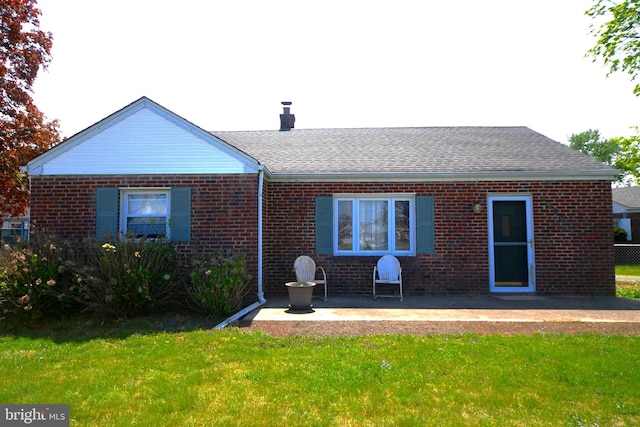 rear view of property featuring brick siding, a patio area, and a lawn